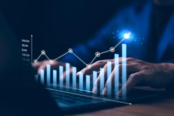 Hands typing on a laptop with glowing bar and line graphs representing data analytics.