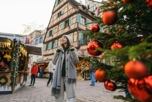 A Caucasian-looking woman walking through a town square in Europe at Christmas