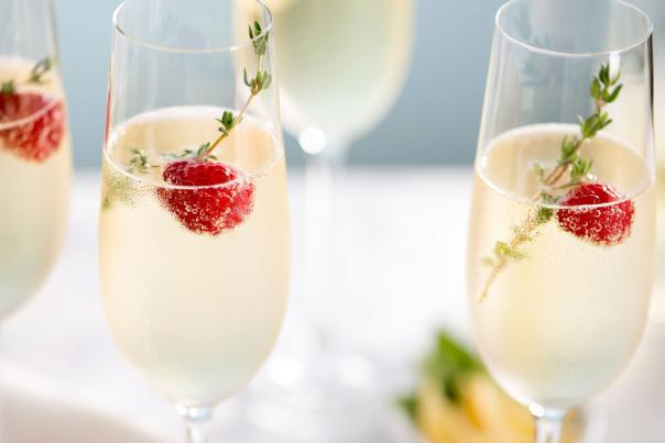 Flutes of sparkling wine with berry and herb garnish