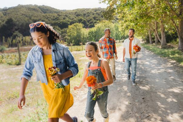 2 kids and 2 adults walking with fresh picked flowers