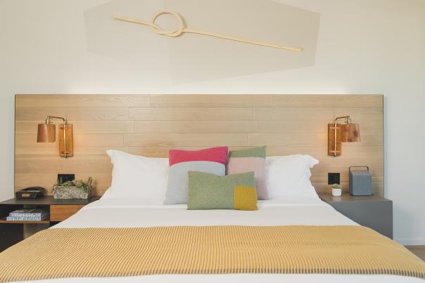 Bed with colorful pillows between two night stands and wall lamps at Hotel SLO