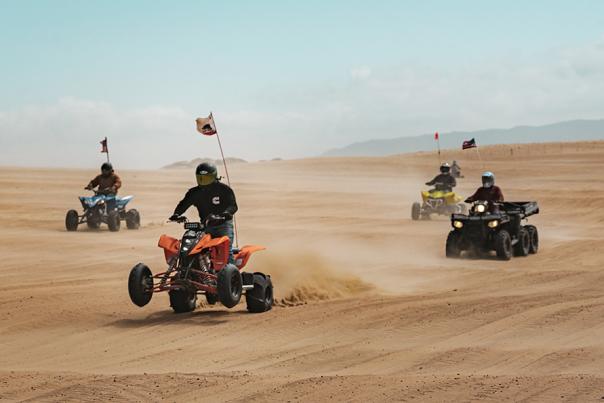 Four people on ATVs riding on sand