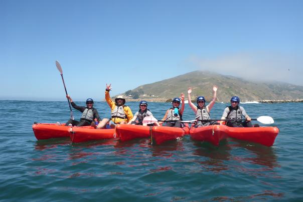 Six kayakers posing for a photo on the water during a tour