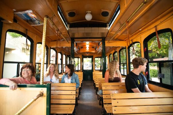 Interior view of five riders on the Old SLO Trolley talking and looking out the window