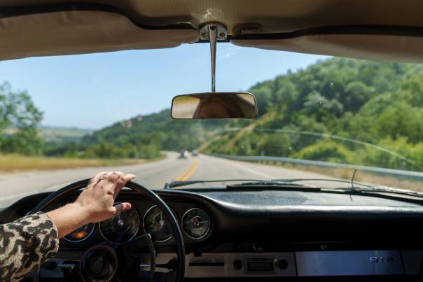 Looking through windshield at road and green hills