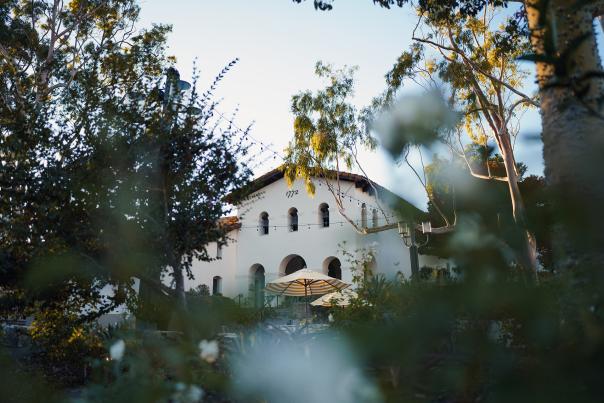 View of mission through the plaza with trees and umbrellas