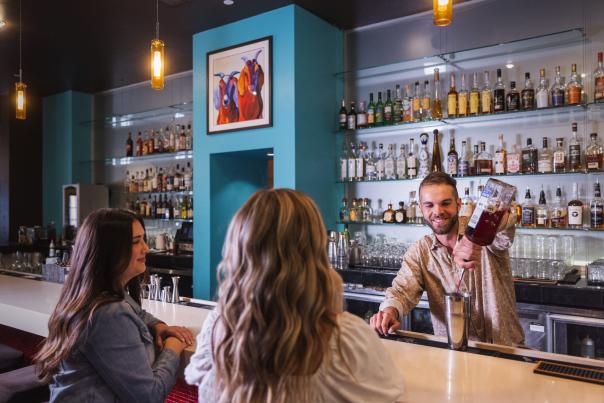 Bartender pouring a drink for two women