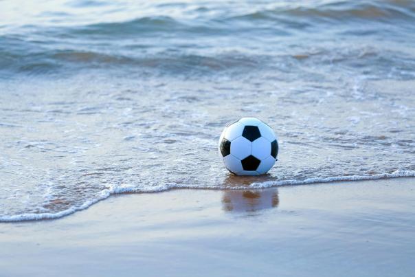 Black and white soccer ball in shallow water on the beach