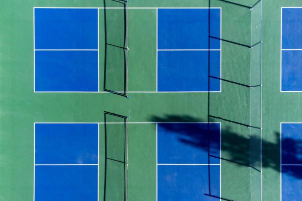Green and blue pickleball courts shown from a birds eye view with 2 in frame and 2 more courts off to the side