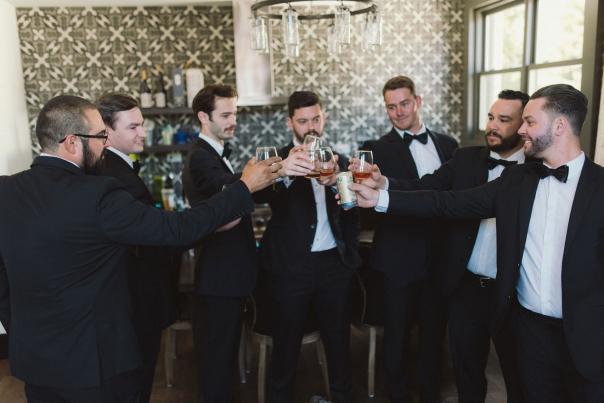 7 men in suits toasting with drinks