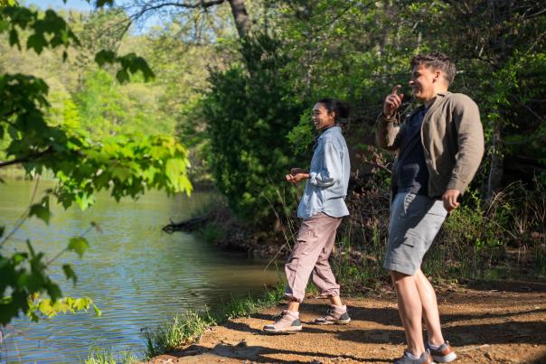 Couple skipping rocks along lakeshore