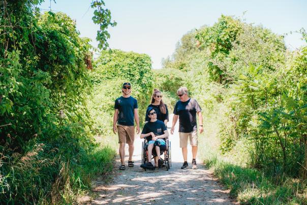 Family with someone in wheelchair walking on a trail
