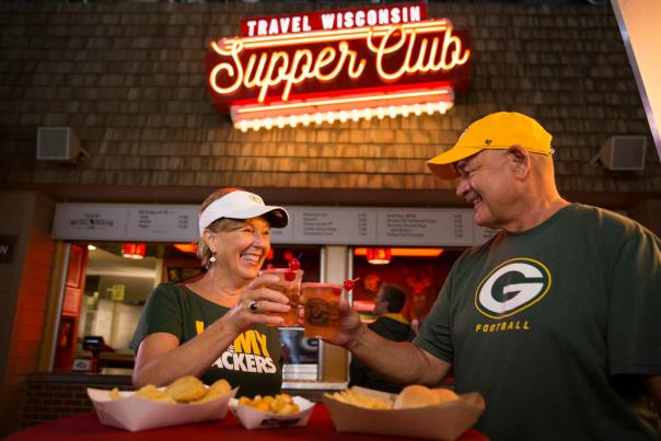 Couple in Packer's gear clinking glasses in front of supper club