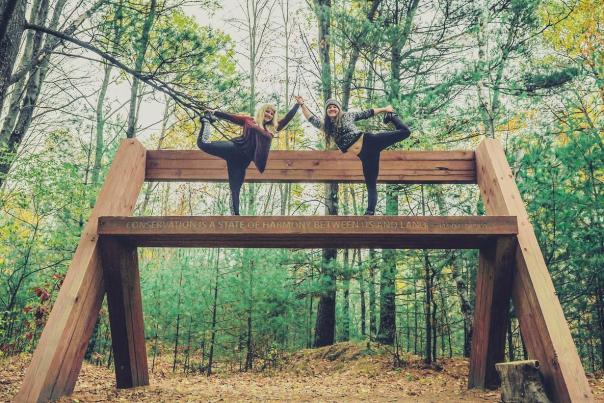 Two women doing yoga on the large bench in the scuplture park.