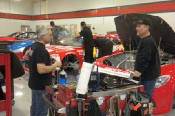 nascar team with their cars in the shop