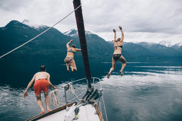 Three people in swimsuits jumping off a boat into the water below.