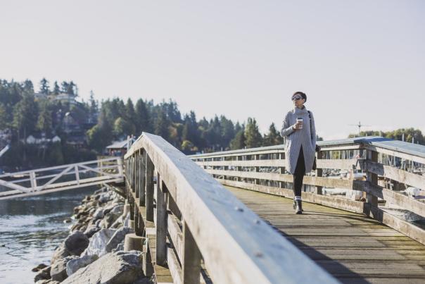 A woman carries a cup of coffee as she walks back from the gazebo in the harbour.