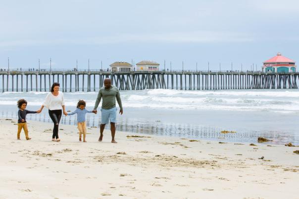 Father's Day in Huntington Beach. Family walking on the sand with the Pier in the background.