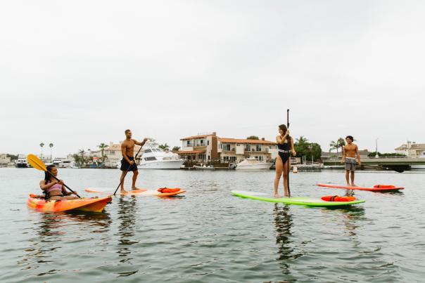 Kayaking in Huntington Harbour. Group of four people kayaking and Stand Up Paddleboarding
