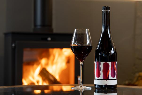 Fireplace with bottle of Artelium Artefact red wine poured in a glass