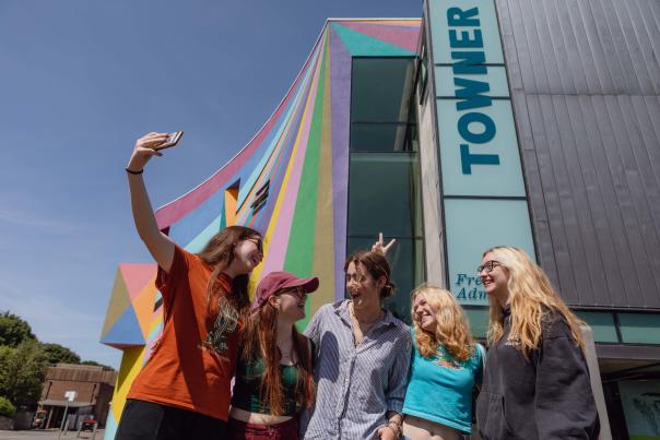 A group of young people take their photo in front of the colourful exterior of Towner gallery, Eastbourne