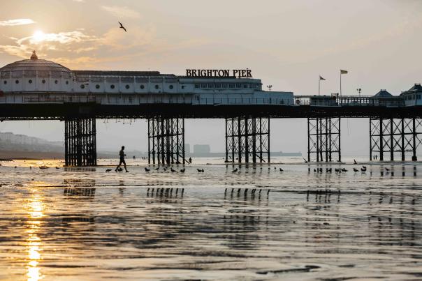 Brighton pier at low tide with the sun rising in the background