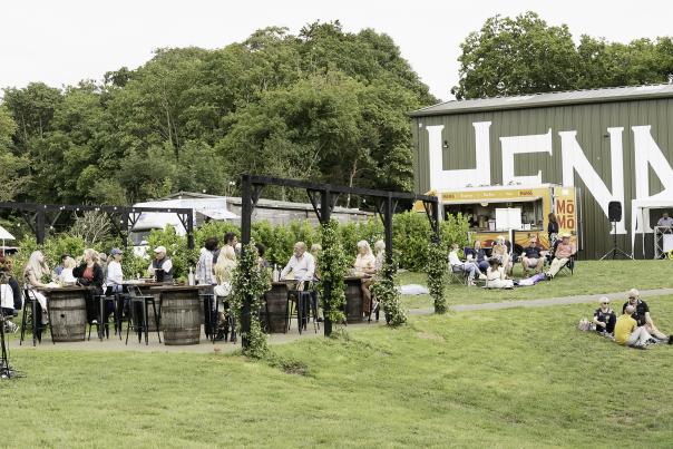 Henners vineyard with a large building in the background and people enjoying al fresco food and drink