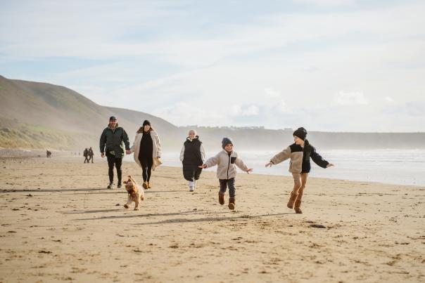A family walking across Llangennith beach, Swansea