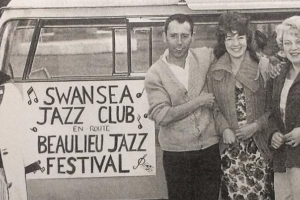 A black and white photo of people in front of the original Swansea Jazz Club banner in the 1950s.