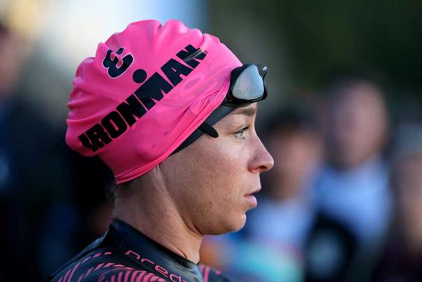 A woman wearing a pink IRONMAN swimming hat