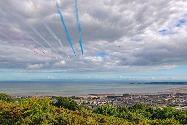 Red Arrows flying over Swansea Bay leaving red white and blue smoke trails.