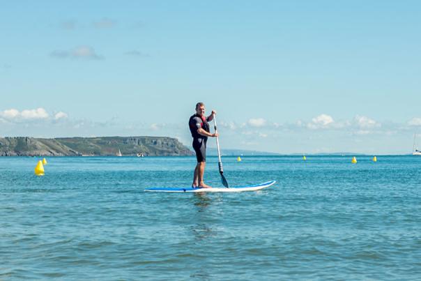 A man on a stand up paddleboard in the sea.