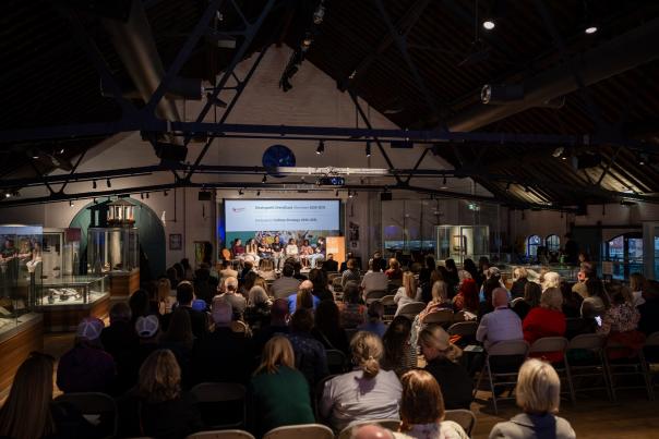 People sitting in the National Waterfront Museum watching the launch of the Swansea Cultural Strategy