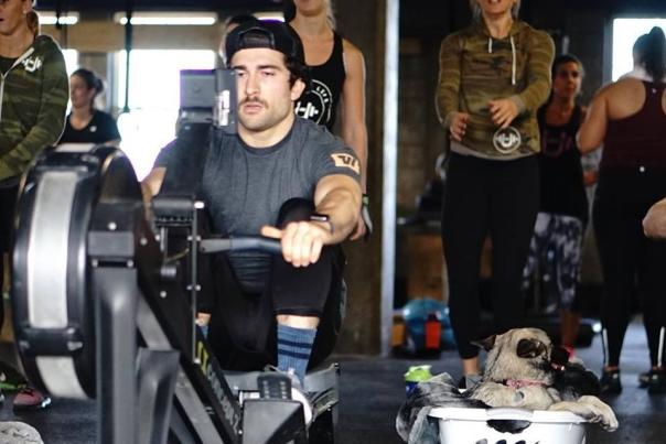 Close-up of a Male Working Out on a Row Machine with People Exercising in Background