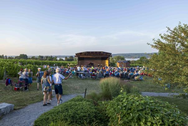 People walking to an outdoor amphitheater in Skaneateles for Skan Fest, overlooking a lake.