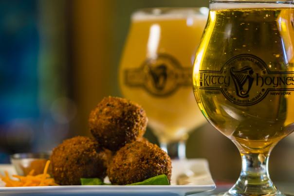 Full Glass of Beer in Kitty Hoynes Glass Next to a Small Appetizer of Fried Veggie Balls