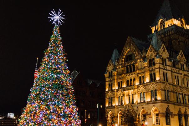 Clinton Square Christmas Tree lit at night with Syracuse Savings Bank building in the background