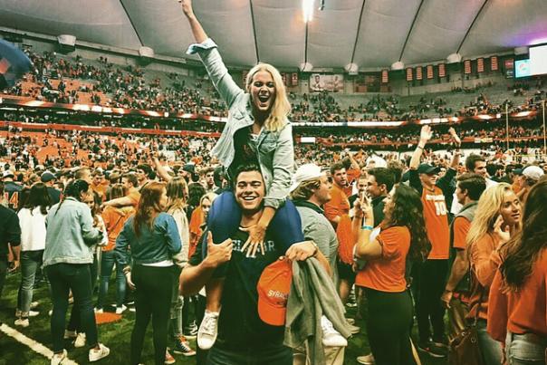 a woman on a man's shoulders in the career dome posing to celebrate a win