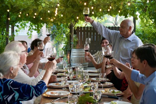 Several people raise their glasses at a table
