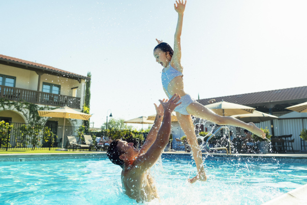 Father and daughter splashing in a pool.