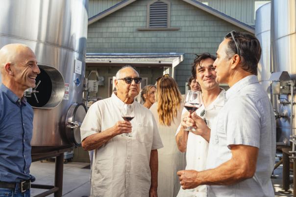 Men Gathered by Winery Production Tanks