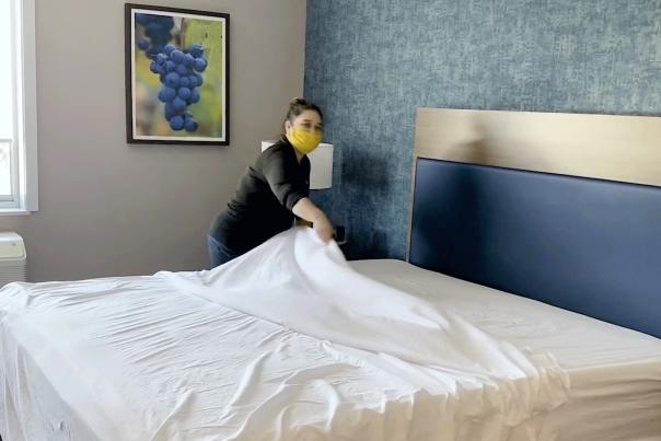 A woman making a bed in a hotel room