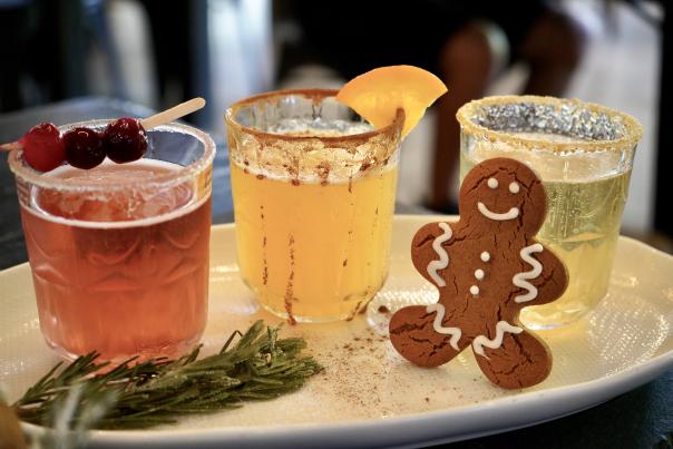 Three mimosas, each of a different juice, sitting alongside a gingerbread man cookie