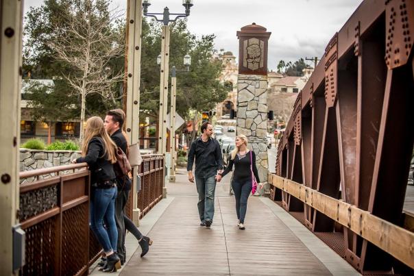 Several people walking and hanging out on an iron bridge