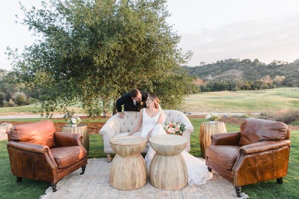 A bride and a groom sit in the outdoor patio of The Oaks at Cross Creek durinf the day