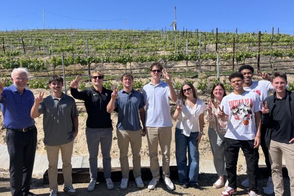 A group of ten students from USC poses in front of a vineyard.