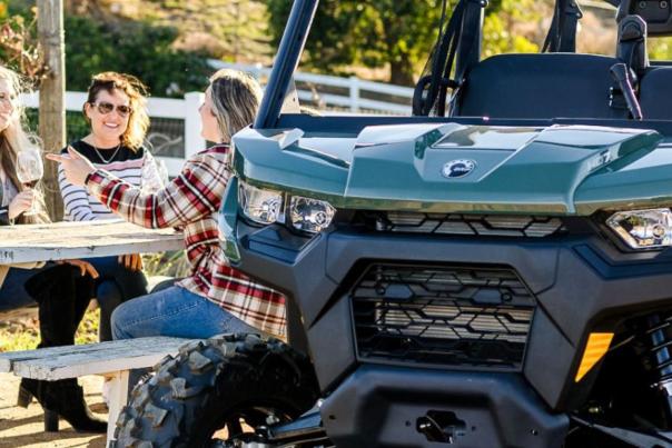 A group of friends sits next to an all terrain vehicle