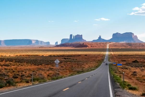 An image of an empty two lane highway surrounded by hills and desert