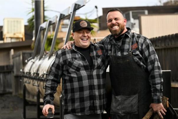 Two men pose, embracing outside the Swing Inn
