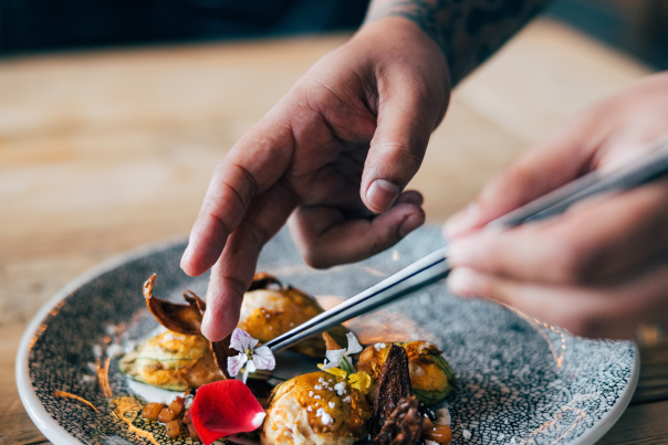 Close up of hands garnishing a plate with decorative flowers